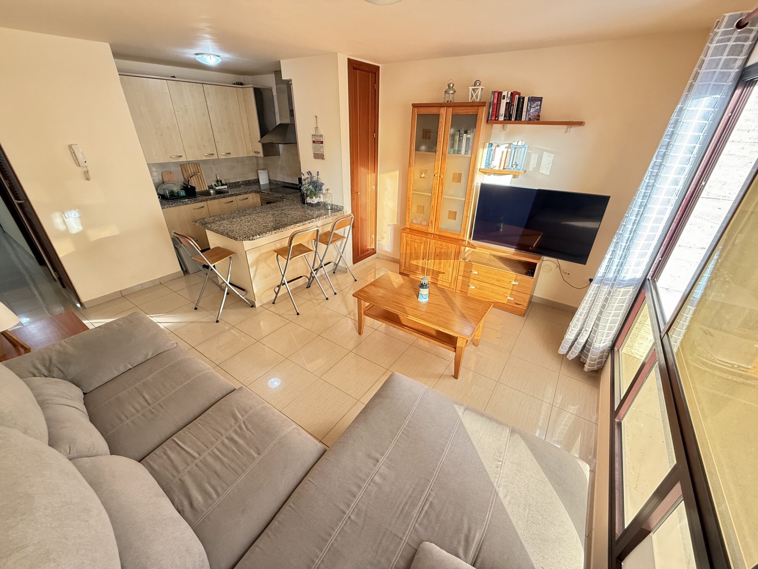 Helles Wohnzimmer mit Flat-TV, Sofa und Vitrine – Ferienwohnung Teneriffa Süd